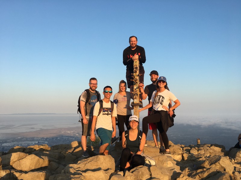 A group of Zooka Team members hiking and posing at the top of the hill.